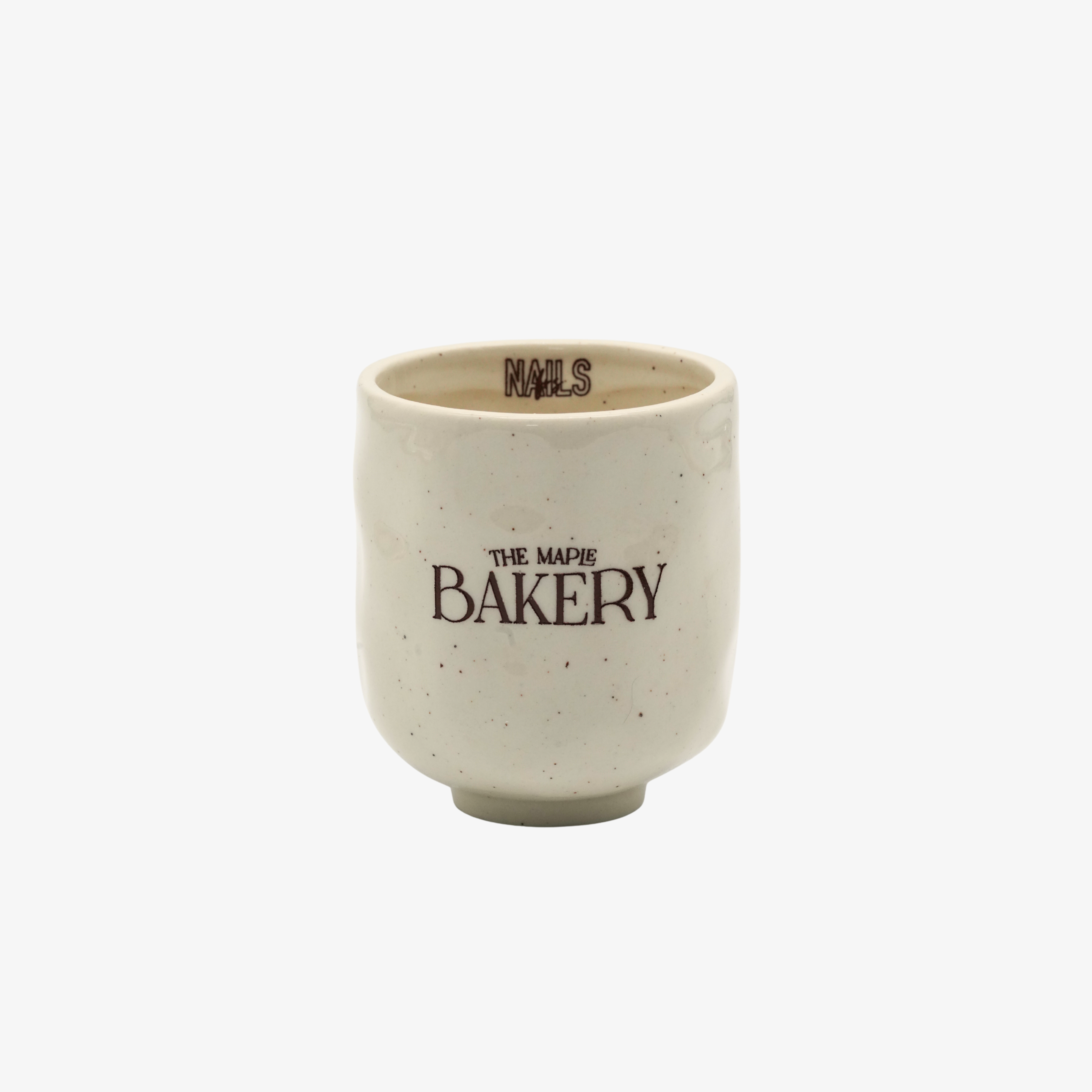 Tasse The Maple Bakery NAILS FRS en céramique crème mouchetée, logo marron et signature NAILS à l'intérieur