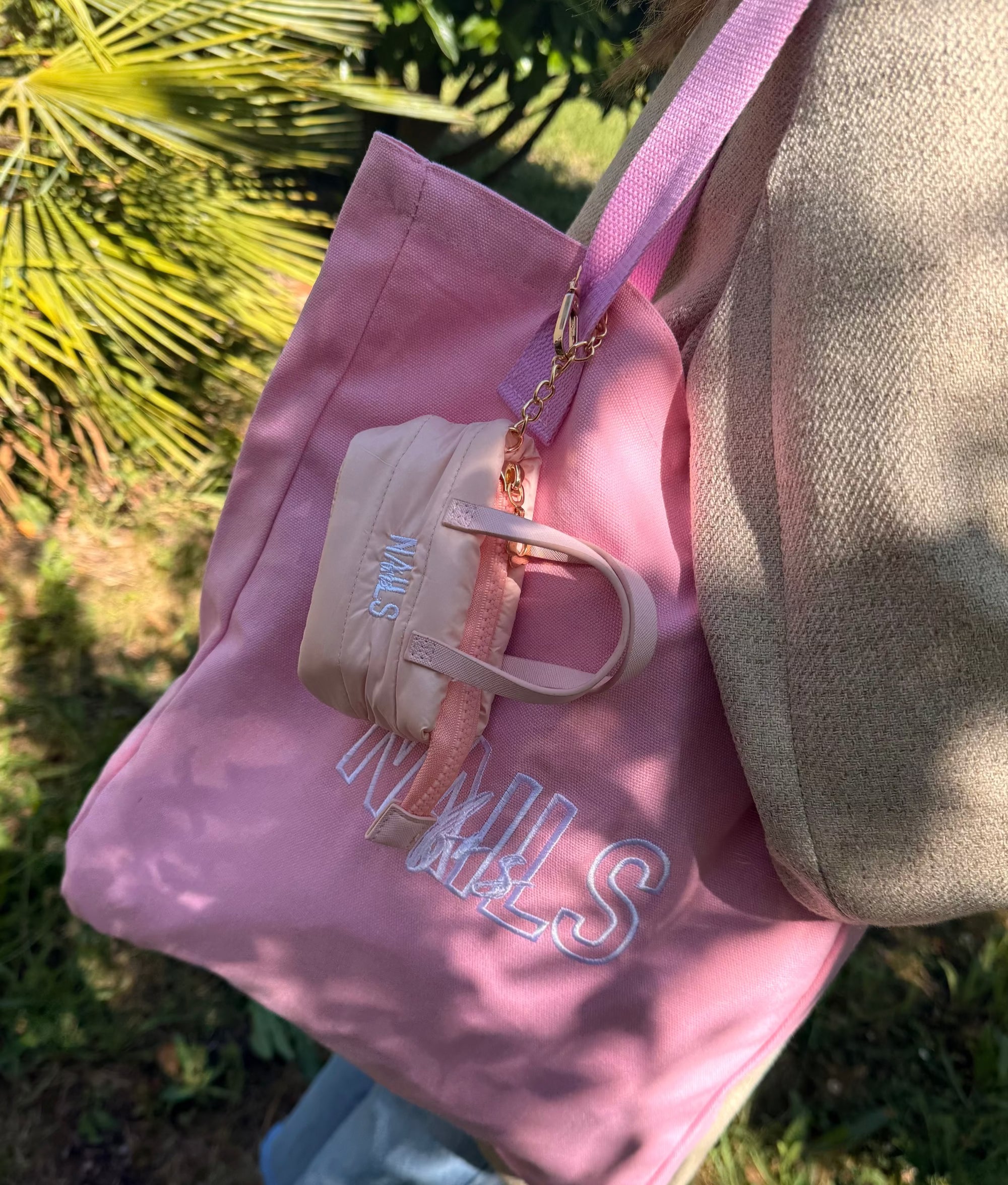 Porte-clés mini-sac NAILS FRS beige accroché à un tote bag rose brodé
